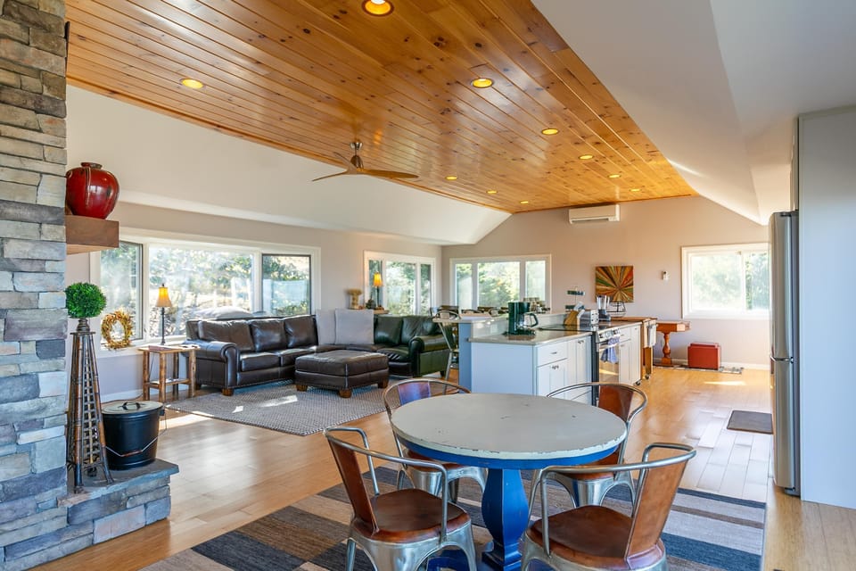 Bright, open gathering space at Alpenglow with a vaulted wood ceiling, stone fireplace, and room for the whole crew.