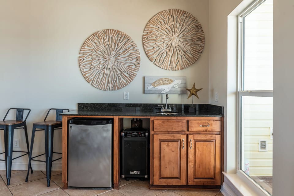 Convenient wet bar located just off the living area, featuring a sink, mini fridge, and storage—perfect for drinks, snacks, and easy entertaining during your Dauphin Island stay.
