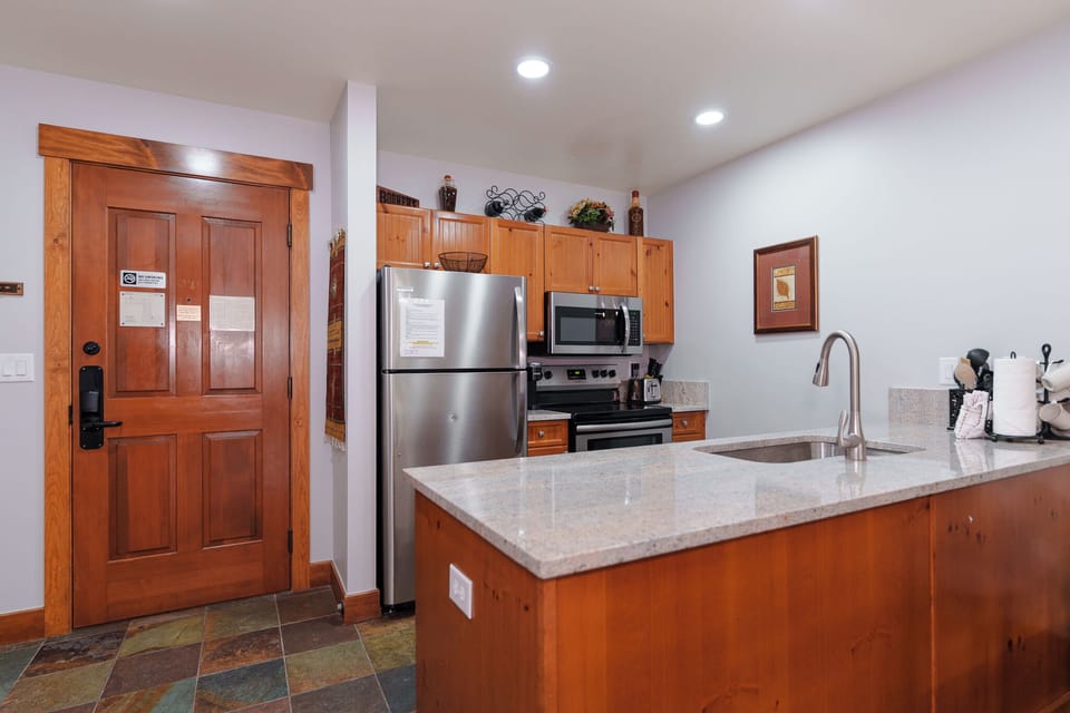Your fully equipped kitchen features granite countertops, stainless steel appliances, and warm wood cabinetry, perfect for preparing meals during your stay.