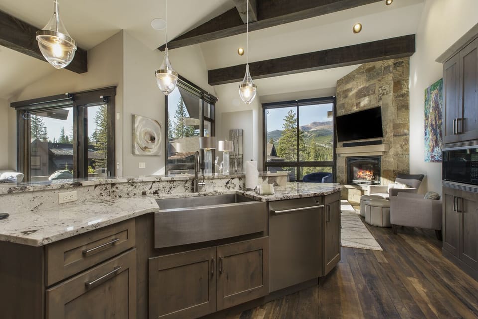 View into the kitchen with double oven, large sink, dishwasher, coffee maker, toaster oven, toaster, microwave, and refrigerator.
