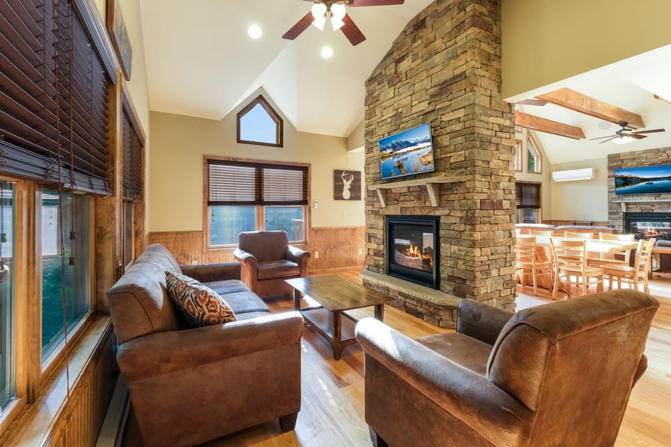 An angled photo of the fireplace of the great room behind the dining table, with seating and TV.