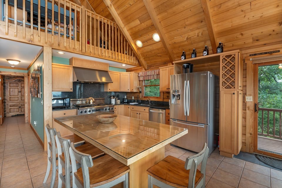 Gourmet kitchen with island seating for 4, 6-burner gas range, dishwasher, and drip-style coffeemaker.