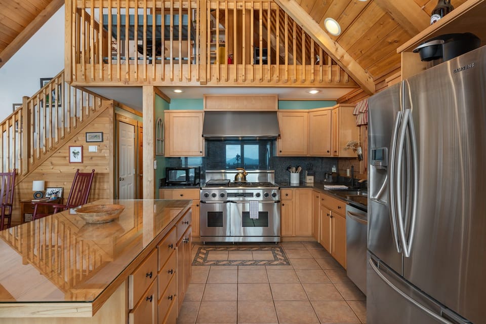 Gourmet kitchen with island seating for 4, 6-burner gas range, dishwasher, and drip-style coffeemaker.