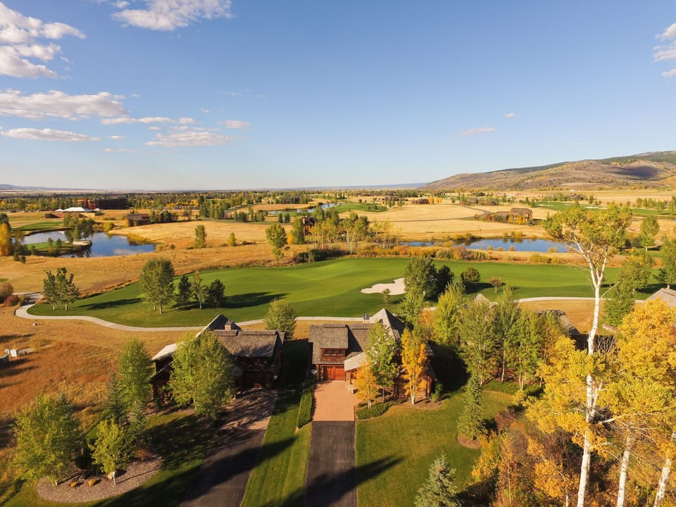Picture yourself waking up to this breathtaking bird's eye view of your private retreat, where golden autumn fields stretch endlessly and your own golf course awaits right outside your door.