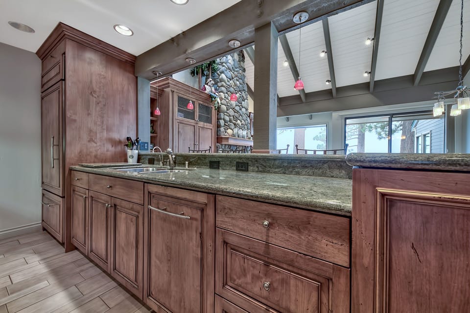 Kitchen with rich wood cabinets, granite counters, and stone fireplace for memorable meal prep.