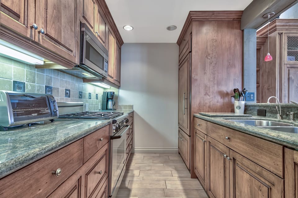 Cook with ease in this elegant galley kitchen featuring rich wood cabinetry, granite countertops, and modern appliances for your culinary adventures.