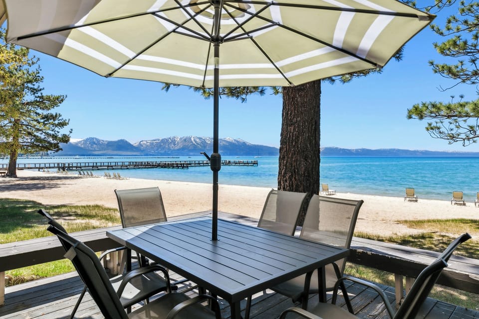 Enjoy lakefront dining at your private table with umbrella shade, overlooking pristine blue waters and snow-capped mountains.