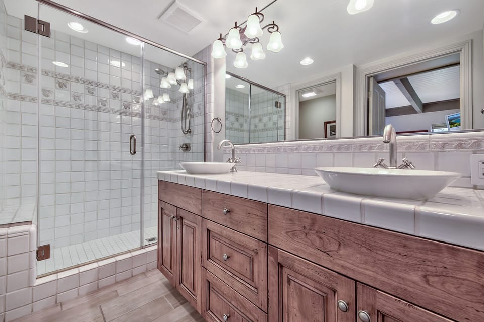 Indulge in this spa-like bathroom with dual vessel sinks, elegant lighting, and a spacious glass shower where you can unwind after your adventures.