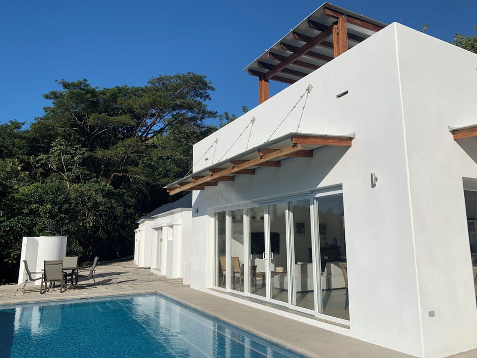 Pool area next to sliding doors to living room and outdoor table and shower
