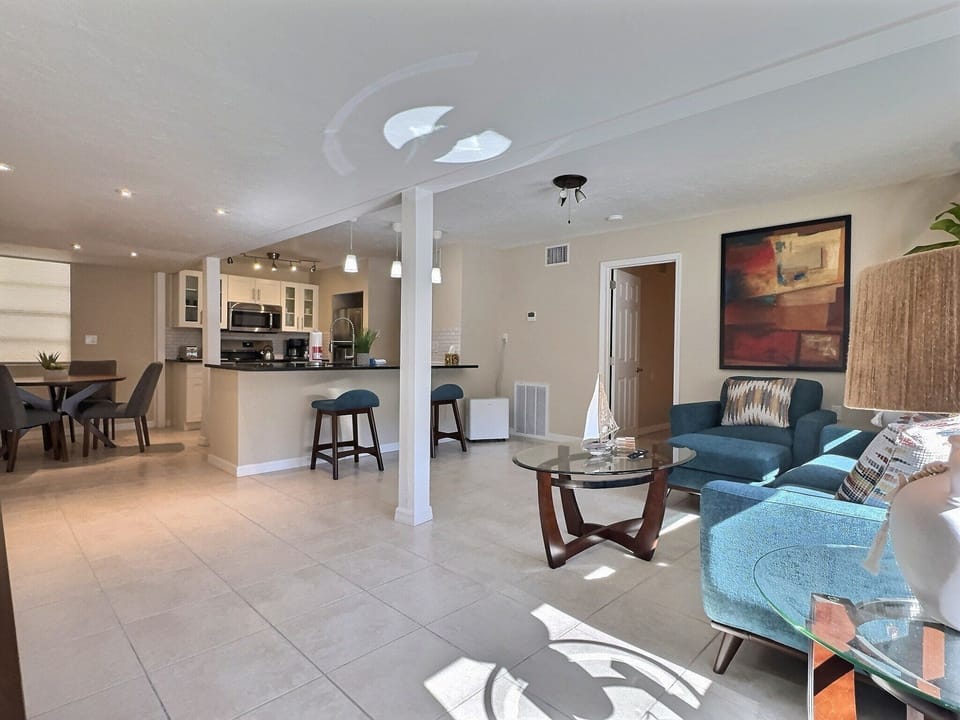 Spacious open living area showcasing comfortable seating, dining table and breakfast bar with views into the kitchen.