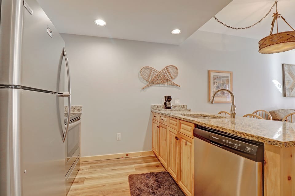 Your fully-equipped kitchen features granite countertops and stainless steel appliances, perfect for preparing meals while you enjoy the rustic mountain charm with decorative snowshoes adorning the walls.