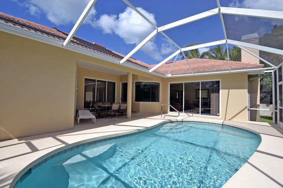 Large screened pool enclosure with oval pool and patio deck viewed from outside