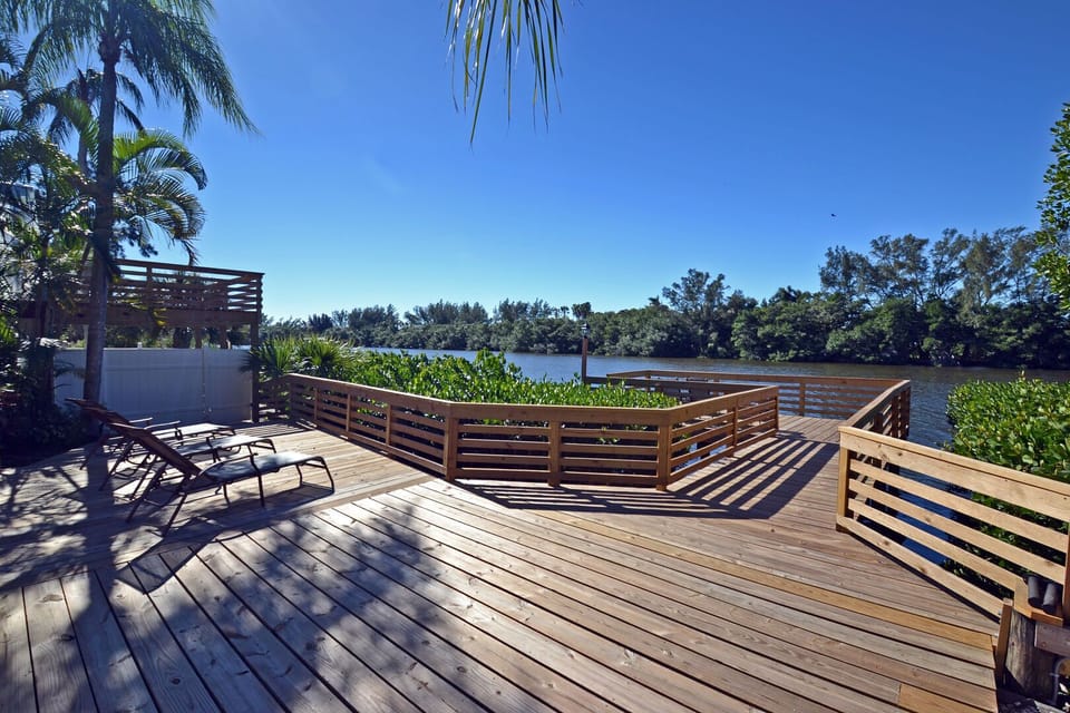 Wooden dock with railing extending over calm water with lush surroundings