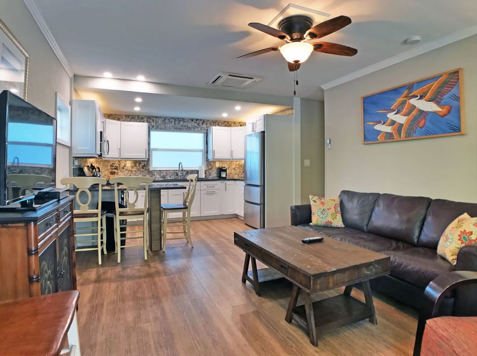 Living room with sofa, coffee table, ceiling fan, and coastal artwork
