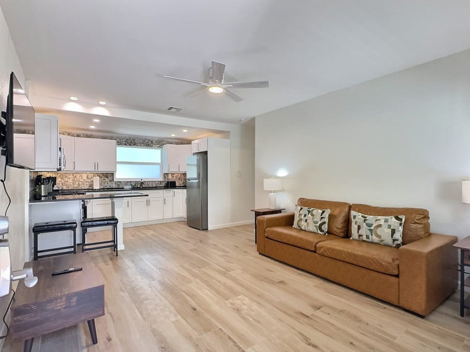 Open-plan living area with sofa, coffee table, and kitchen visible in background