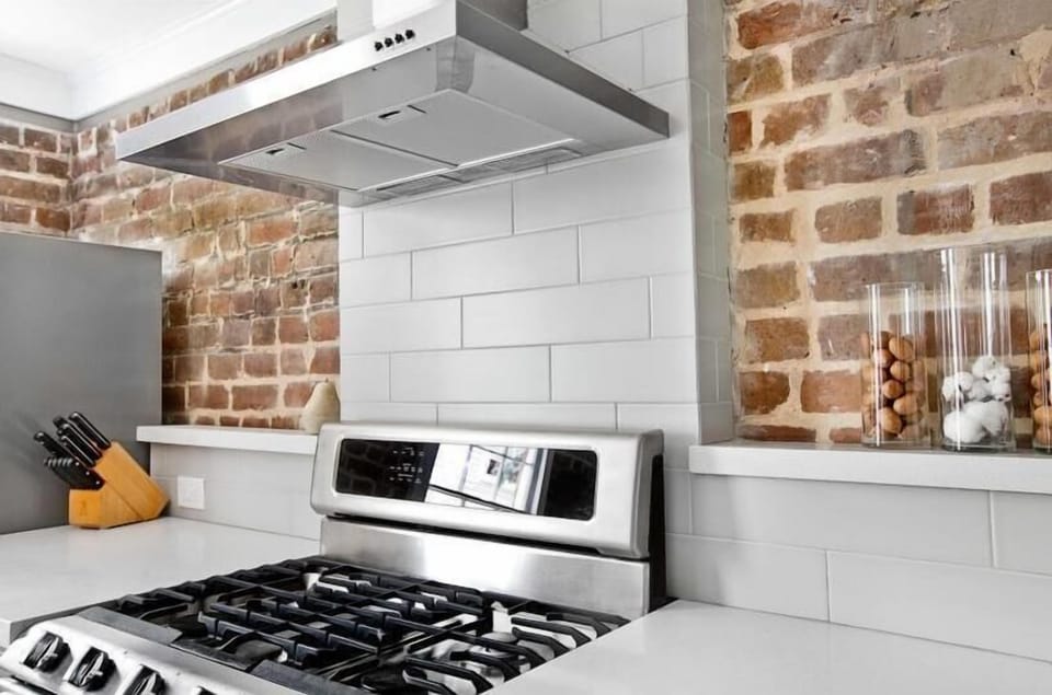 Contemporary subway tile back splash and stainless steal gas stove.