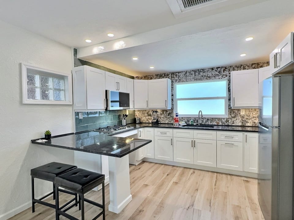Updated kitchen with white cabinets, stainless appliances, and bar seating
