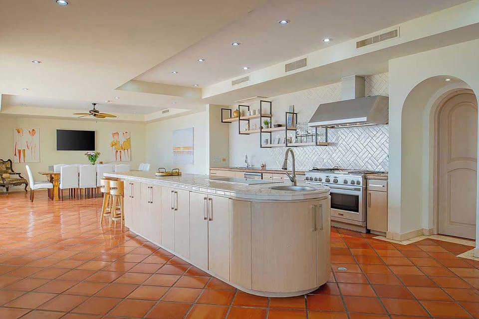 Step into your dream kitchen where warm terracotta tiles meet sleek modern design—a spacious island invites you to prepare meals while taking in the open flow to your dining area.