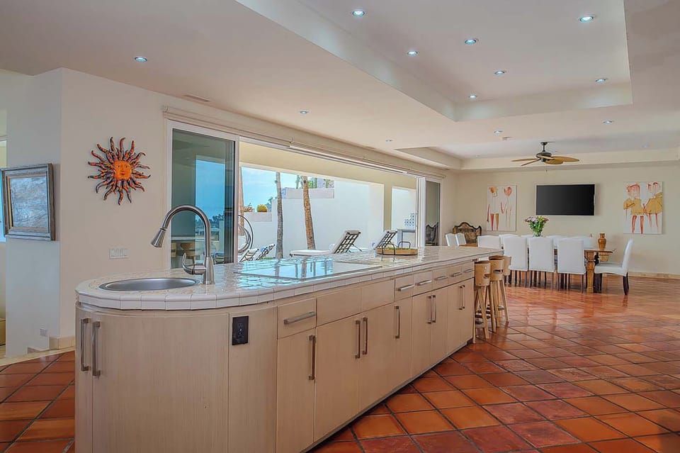 Enjoy your morning coffee in this bright open-plan space featuring a sleek modern kitchen with terracotta tile flooring flowing into a comfortable dining area.