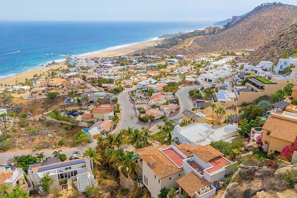 A stunning coastal community nestled between rolling hillsides and pristine sandy beaches, where palm-lined streets wind through charming residences with sparkling ocean waters just beyond.