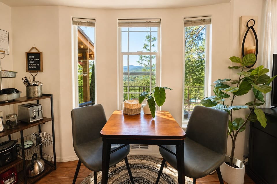 Picture yourself enjoying morning coffee at this inviting dining table, sunlight streaming through large windows that frame stunning mountain vistas. The warm wood tones and lush greenery create the perfect spot to linger over breakfast.