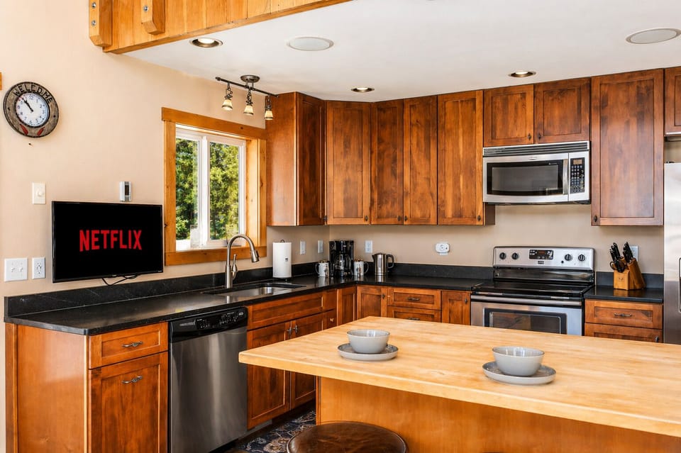 Your fully-equipped kitchen features warm wood cabinetry, modern appliances, and a spacious island perfect for preparing meals and enjoying morning coffee together.