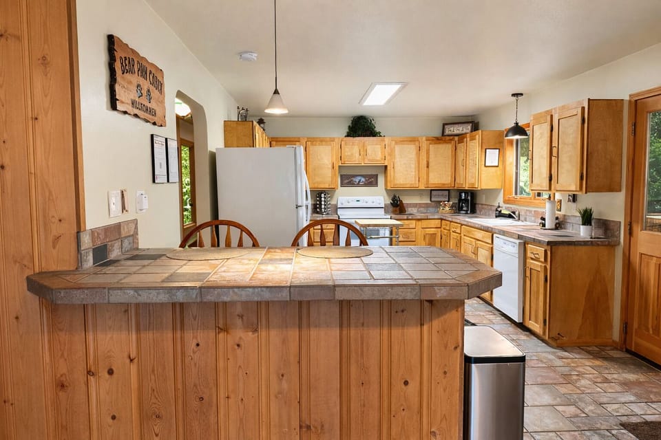 Your spacious kitchen features warm wood cabinets, tiled counters, and a breakfast bar perfect for morning coffee and meal prep.