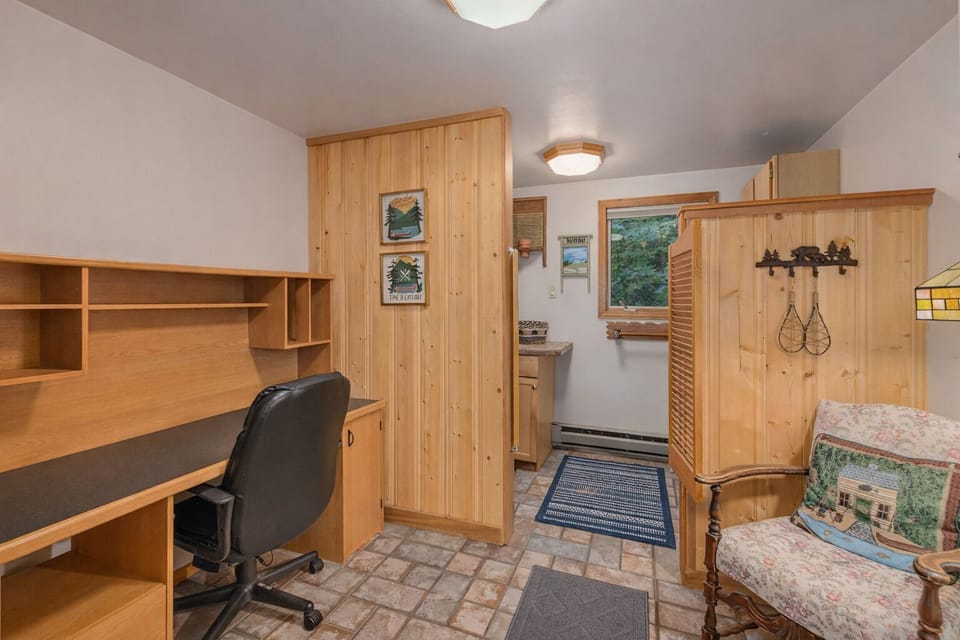 Your cozy workspace features warm wood furnishings, built-in shelving, and comfortable seating surrounded by charming rustic touches.