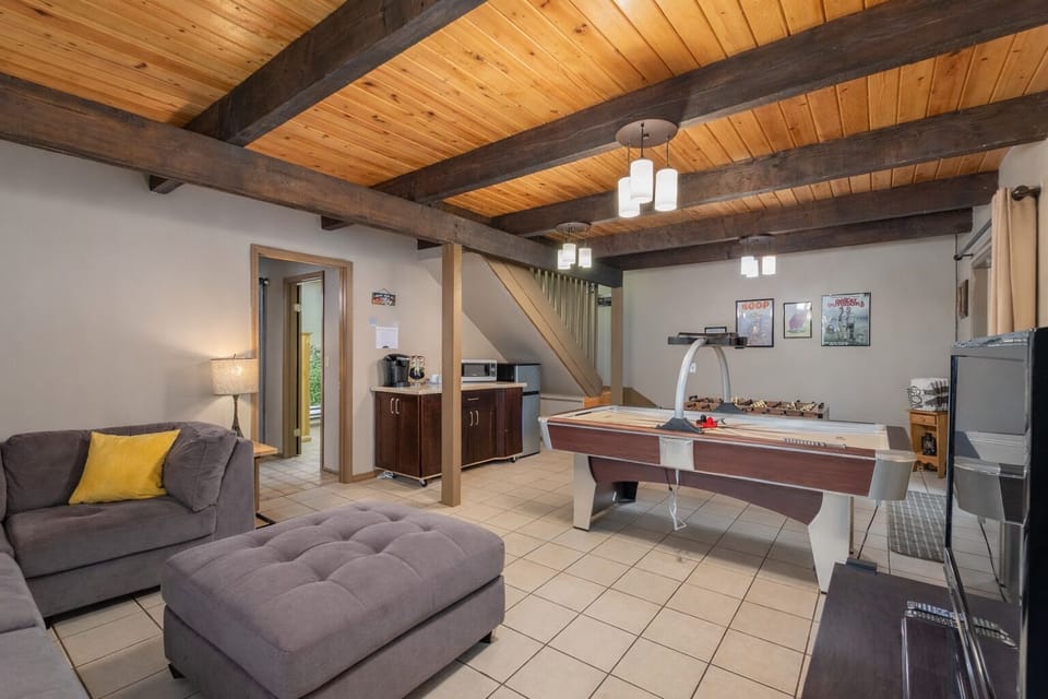 Relax in your rustic-modern retreat with exposed beams, cozy seating, and an air hockey table for endless entertainment.
