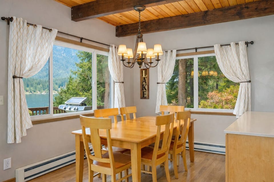 Gather for memorable meals in your charming dining room, where rustic wood beams frame stunning lake and mountain views through expansive windows.