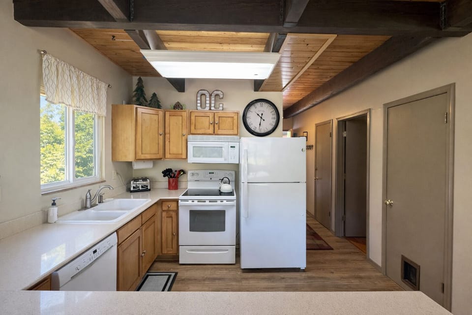 Your fully equipped kitchen invites home-cooked meals with warm wood cabinets, modern appliances, and charming exposed beam ceiling details.