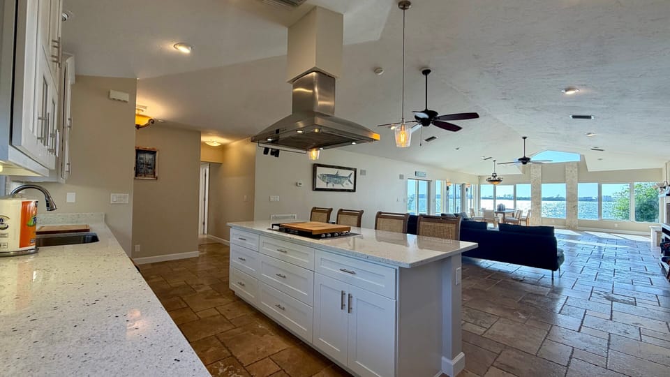 Open-concept kitchen with center island flowing directly into the great room, with ceiling fan and natural light throughout