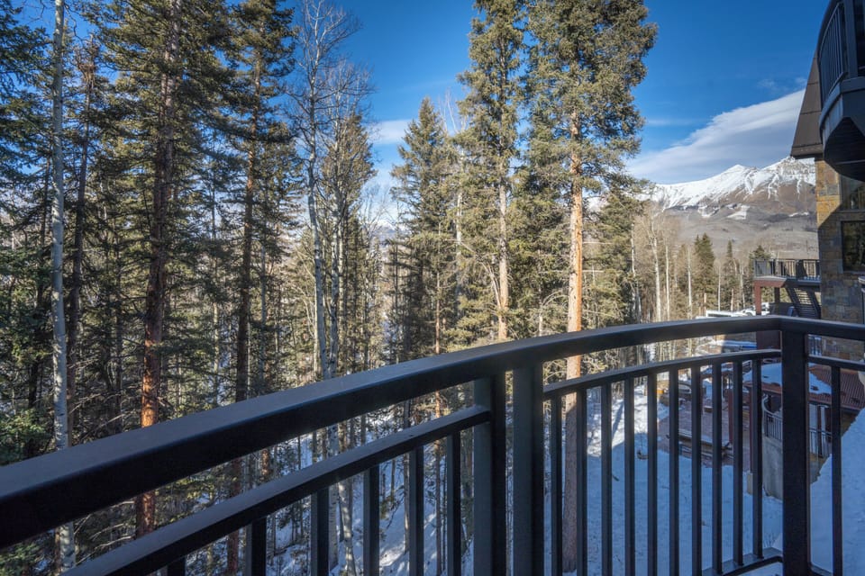 Step onto your private balcony where snow-dusted pines frame majestic mountain peaks, creating the perfect winter retreat backdrop.