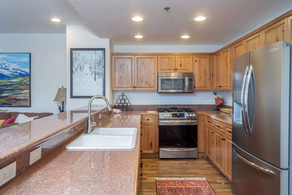 Cook your favorite meals in this fully equipped kitchen featuring granite counters, stainless steel appliances, and rich wood cabinetry.