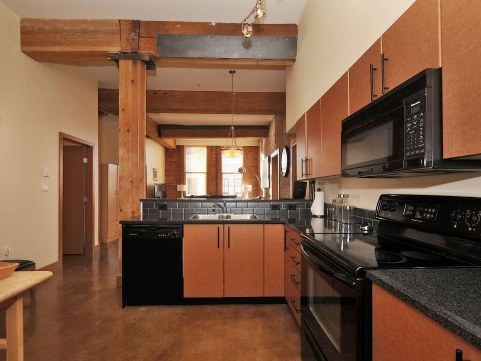 A chef's dream! This spacious kitchen setup offers full-size black appliances, double sinks, and abundant cabinet storage.
