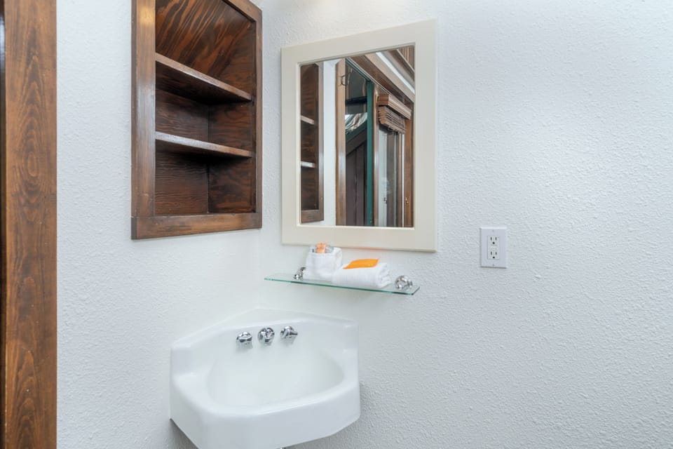 Freshen up at your charming corner sink with custom wood shelving and thoughtful touches that make every moment feel like home.