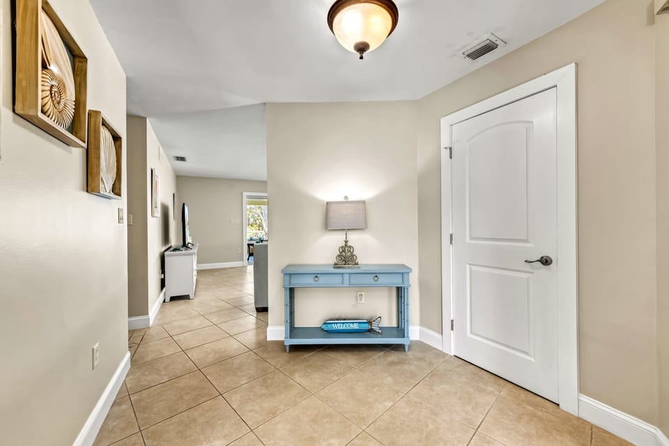Looking inward from the entry, a soft blue console table adds a pop of color to the foyer, while a subtle view into the living room hints at the comfort and charm that lies ahead.