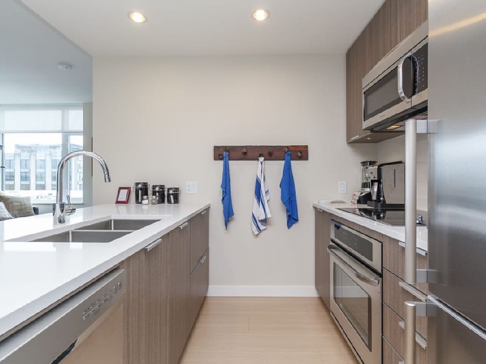 Cook with ease in a sleek, fully equipped kitchen featuring built-in appliances, a microwave, and flat-panel cabinetry.