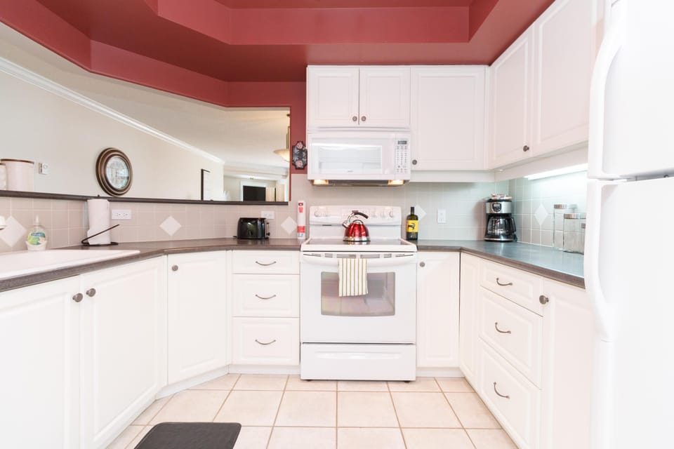 Cook with joy in this bright kitchen featuring white appliances, ample cabinetry, and recessed ceiling details.