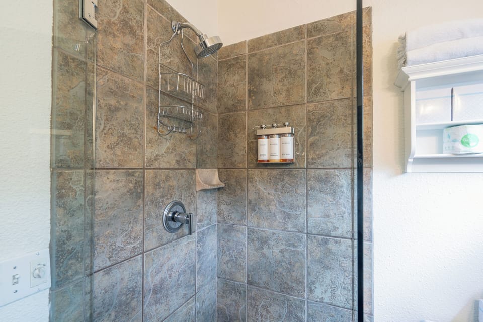 Your private bathroom features a spacious walk-in shower with elegant stone tile, handheld fixtures, and thoughtfully stocked amenities for a refreshing, spa-like experience.