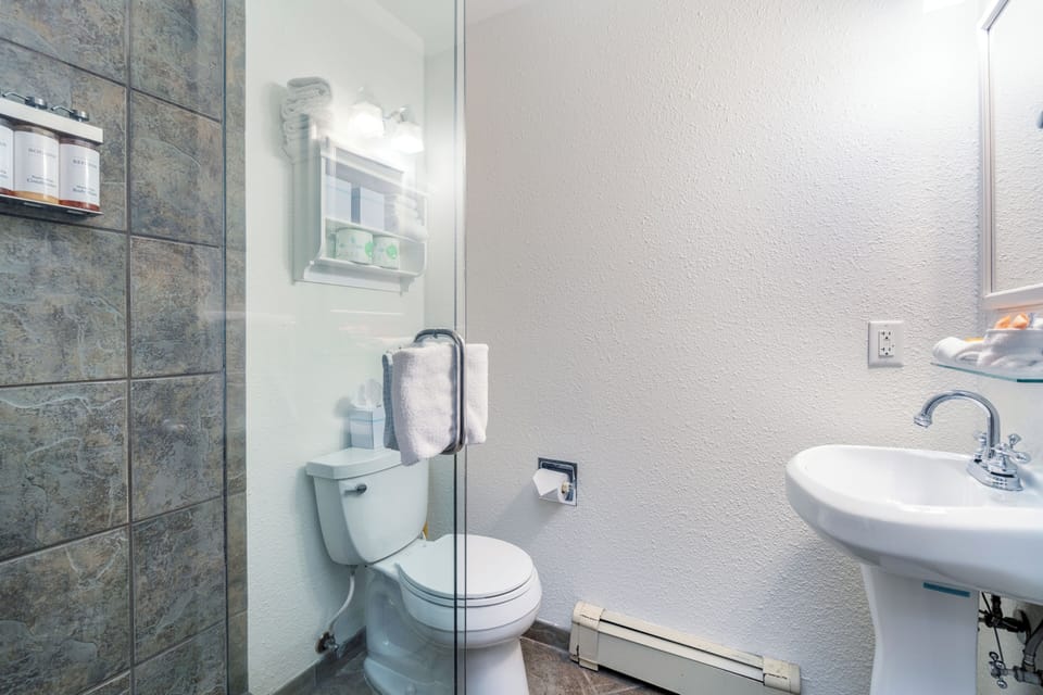 Your private bathroom features a walk-in shower with elegant stone tile, bright lighting, and all the essentials to refresh after a day of exploring.