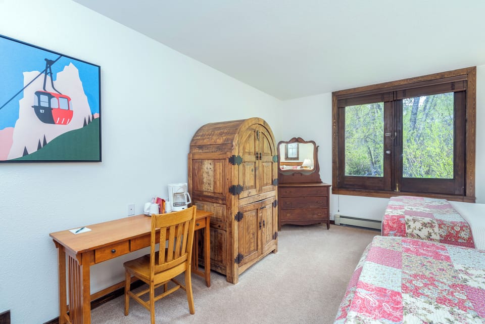 Your comfortable bedroom features rustic wood furnishings, a charming mountain-view window, and a cozy work desk—perfect for unwinding after a day of mountain adventures.