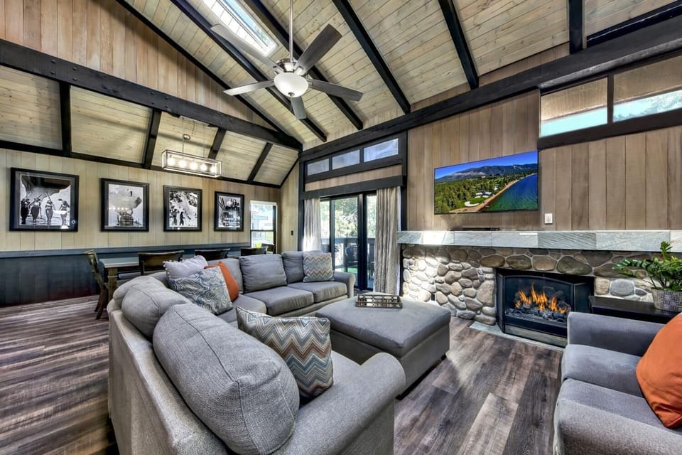 Relax in this stunning living room with vaulted ceilings, cozy fireplace, and modern entertainment system for your perfect getaway.