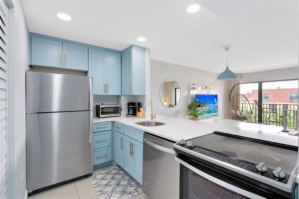 Fully equipped kitchen with brand-new appliances, stylish blue cabinetry, and in-unit washer and dryer.