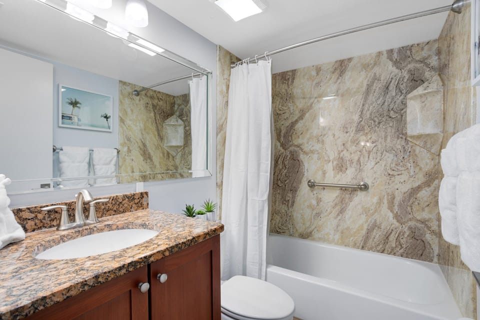 Luxurious bathroom featuring a granite vanity and a stone-accented bathtub