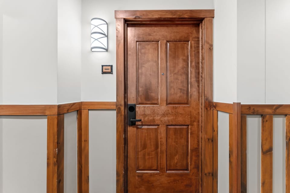 Your suite awaits behind this welcoming wooden door with rustic wainscoting and modern keyless entry for seamless arrival.