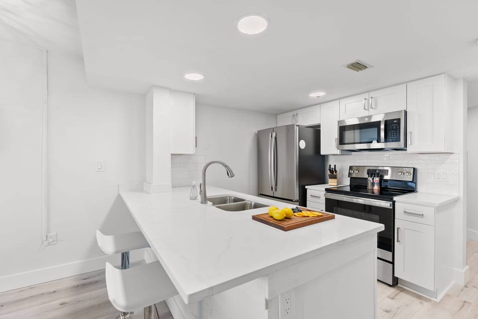 Modern kitchen with a sleek breakfast bar, white cabinetry, and stainless steel appliances.
