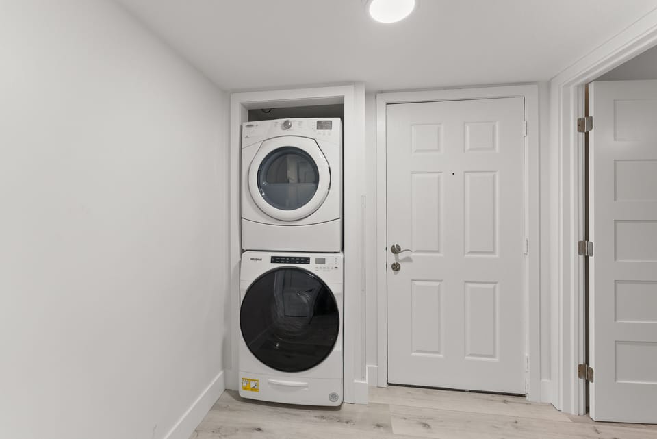 Convenient in-unit laundry with a stacked washer and dryer in a clean, organized space.