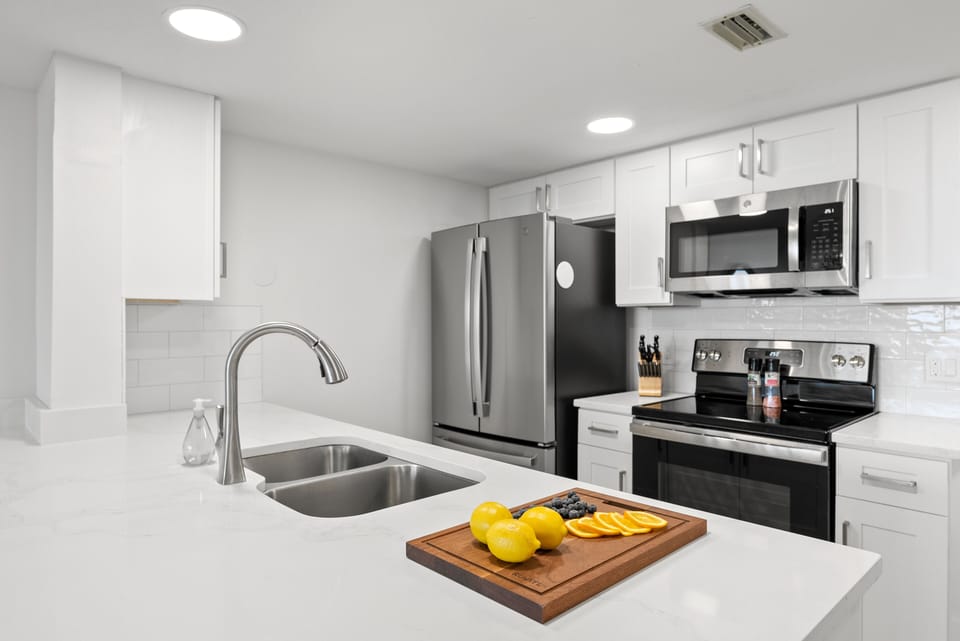Bright and contemporary kitchen with a large sink, stainless steel appliances, and a minimalist design.