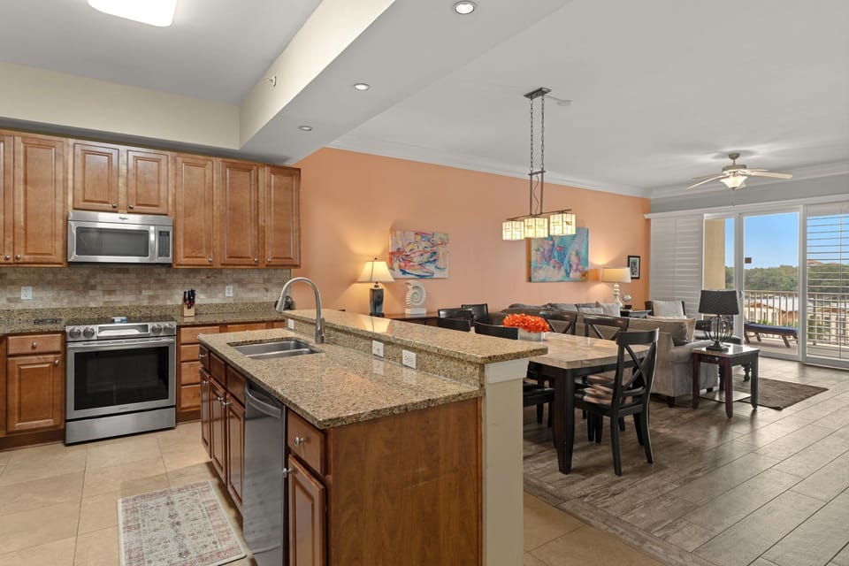 This open-concept kitchen and living space invites relaxed gatherings with granite countertops, stainless appliances, and natural light flowing in from the balcony doors.